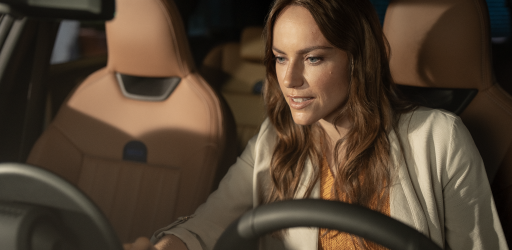A woman looks down at the MINI OLED Display from the driver’s seat of her MINI.