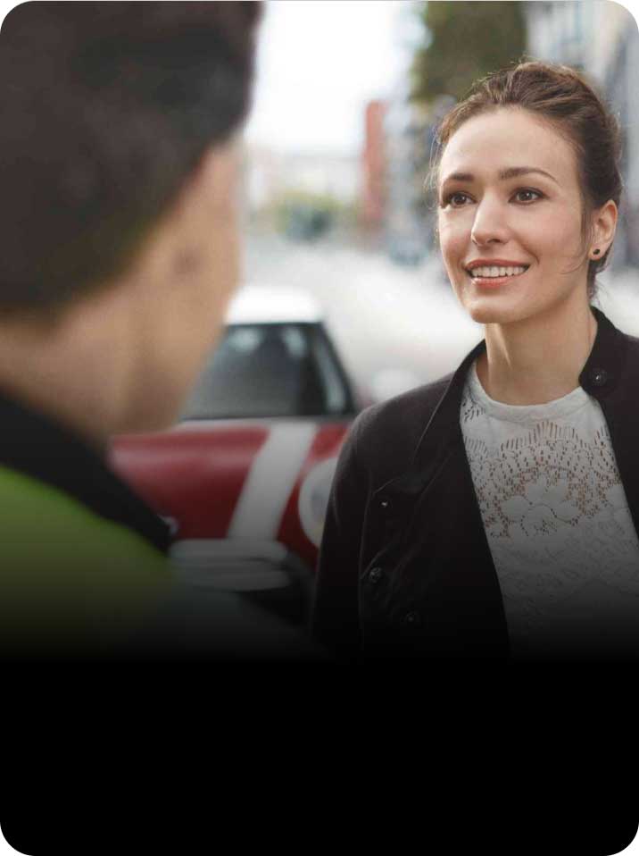 A woman smiles towards a Roadside Assistance professional.