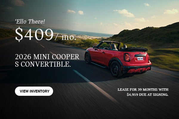 Rear view of a red MINI Convertible driving down a hill.